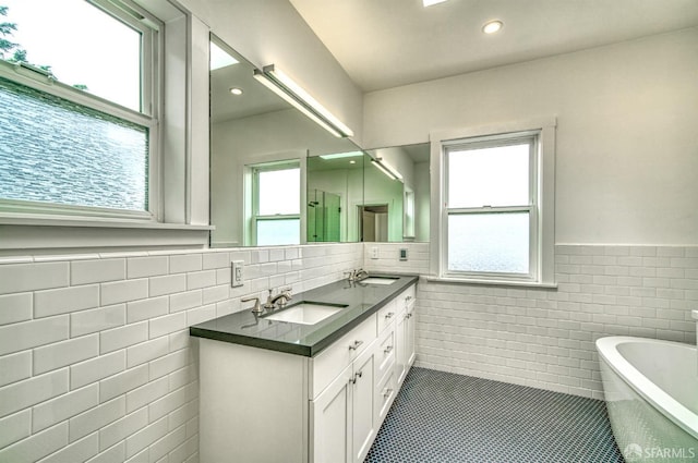 bathroom featuring tile patterned flooring, vanity, tile walls, and a tub