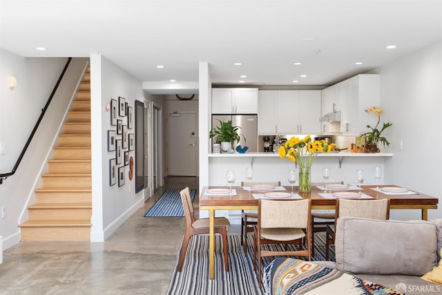 dining area featuring concrete flooring, recessed lighting, baseboards, and stairs