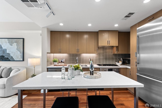 2655 Bush St Unit 119, San Francisco, CA 94115 - kitchen with stainless steel appliances, light countertops, wood finished floors, decorative backsplash, and recessed lighting