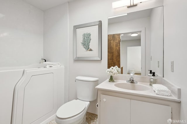 bathroom featuring vanity, a washtub, and toilet