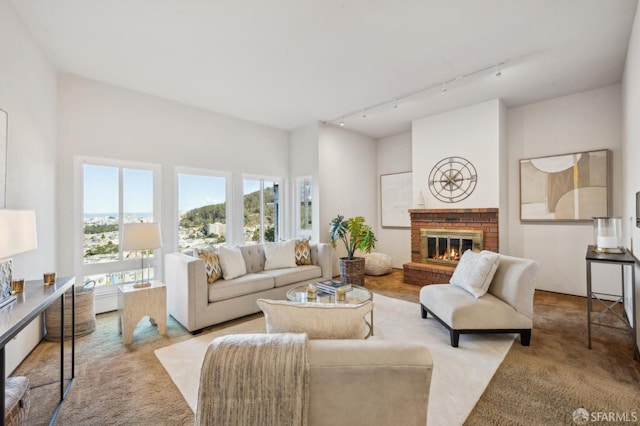 carpeted living room featuring track lighting and a brick fireplace