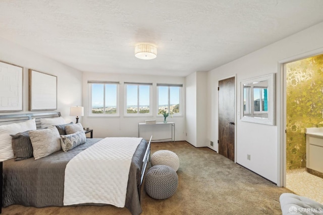 carpeted bedroom with connected bathroom and a textured ceiling