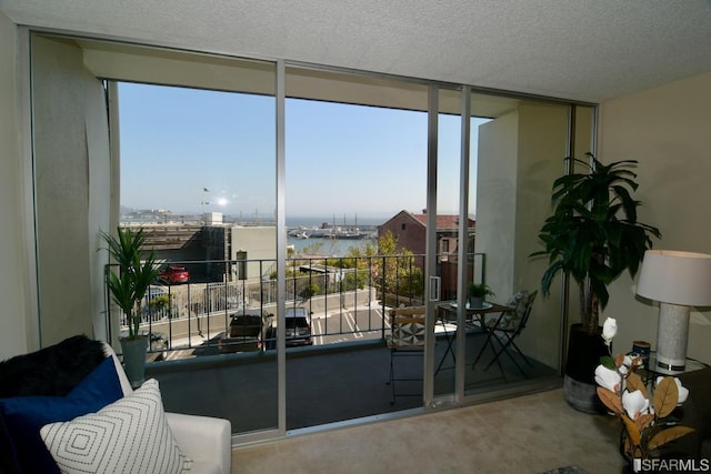 interior space with expansive windows, a water view, plenty of natural light, and a textured ceiling