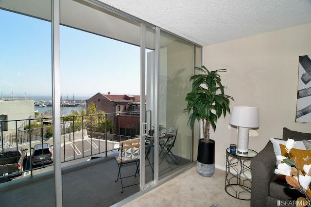 interior space featuring a water view, a wall of windows, and a textured ceiling