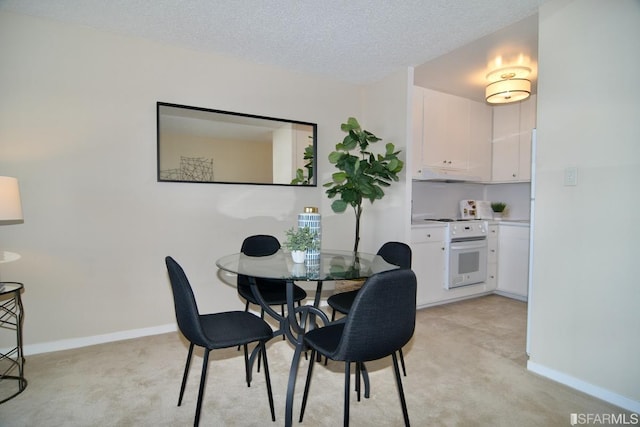 dining room featuring a textured ceiling, baseboards, and light colored carpet