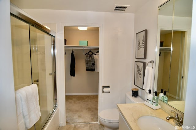 full bathroom featuring a walk in closet, shower / bath combination with glass door, visible vents, toilet, and vanity