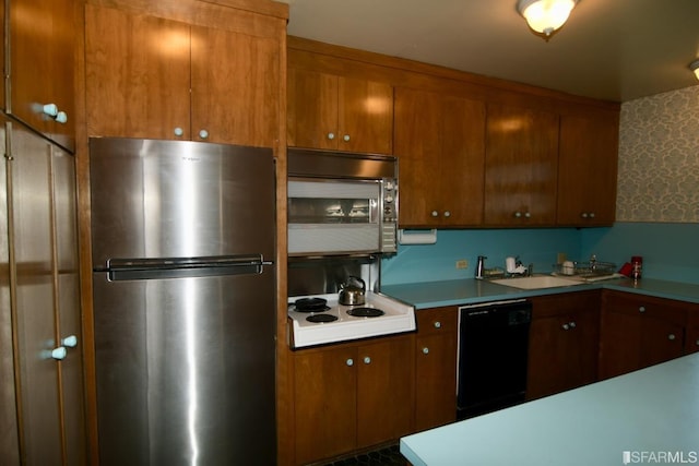 kitchen with brown cabinetry, stainless steel appliances, a sink, and light countertops