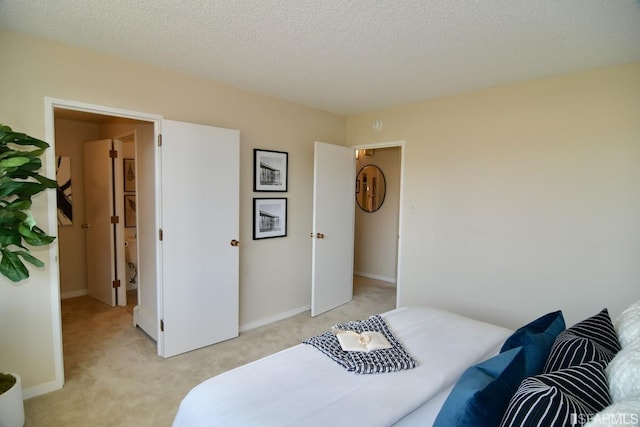 bedroom with light colored carpet, a textured ceiling, and baseboards