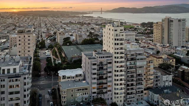 aerial view at dusk featuring a water and mountain view and a city view