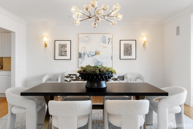 dining area with light wood-type flooring, an inviting chandelier, and ornamental molding