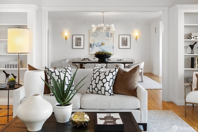 living area featuring baseboards, ornamental molding, a notable chandelier, and wood finished floors