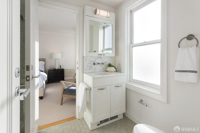 ensuite bathroom featuring ensuite bathroom, vanity, ornamental molding, backsplash, and radiator heating unit