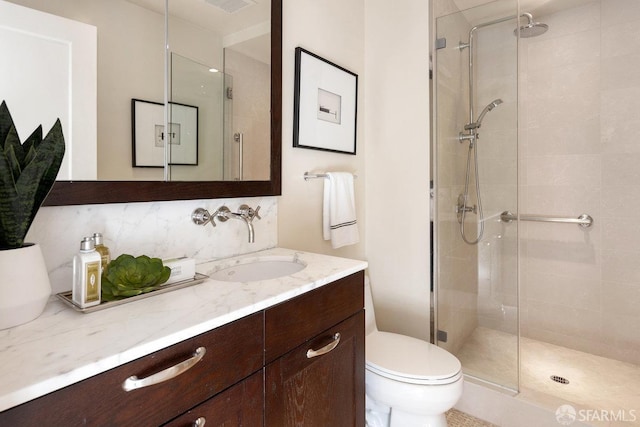 bathroom with a shower stall, toilet, backsplash, and vanity