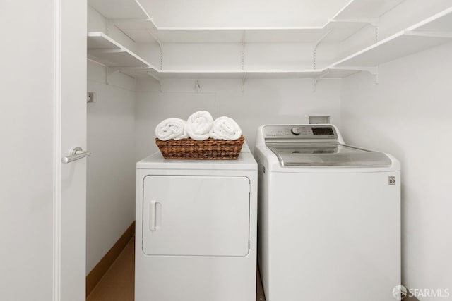 clothes washing area with laundry area, independent washer and dryer, and baseboards