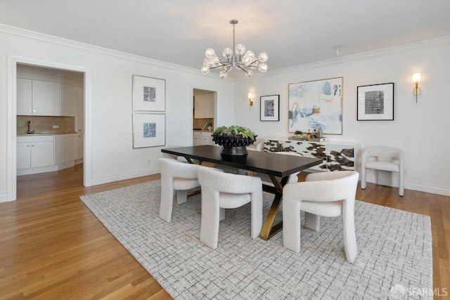 dining area with baseboards, ornamental molding, light wood-type flooring, and a notable chandelier