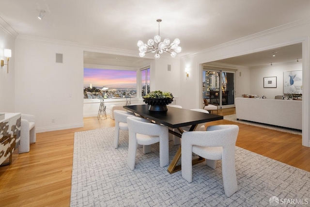 dining room with ornamental molding, light wood finished floors, visible vents, and a notable chandelier