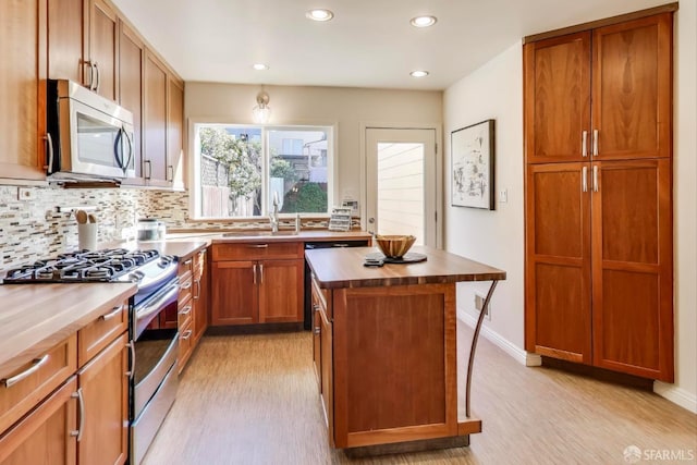 kitchen with sink, wooden counters, appliances with stainless steel finishes, a center island, and decorative backsplash