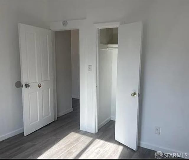 unfurnished bedroom featuring a closet, baseboards, and wood finished floors