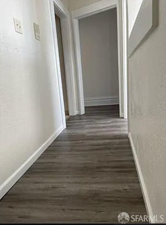 hallway with dark wood-type flooring and baseboards