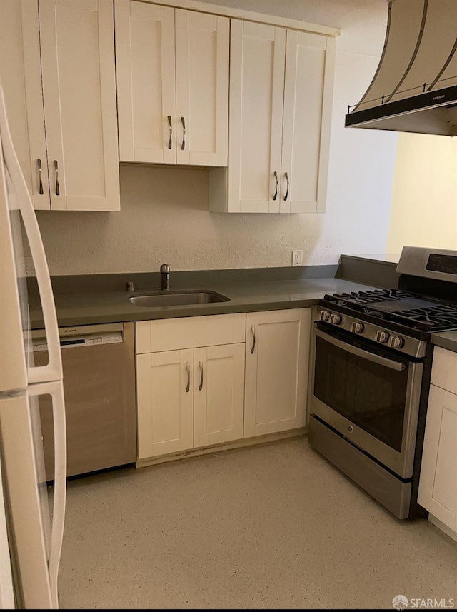 kitchen featuring white cabinets, a sink, dark countertops, and appliances with stainless steel finishes