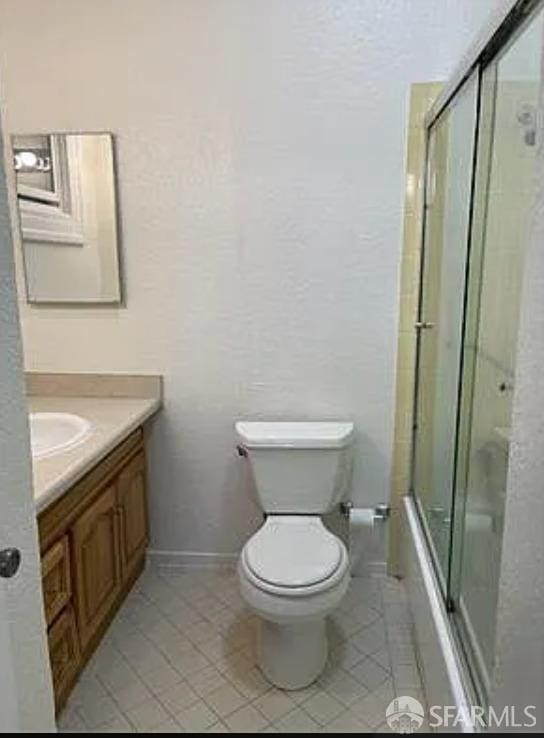full bathroom featuring combined bath / shower with glass door, tile patterned floors, toilet, vanity, and baseboards