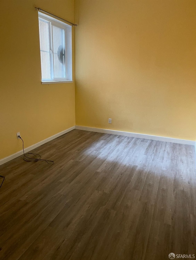 empty room with baseboards and dark wood finished floors