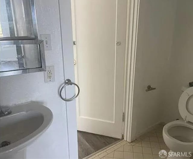bathroom with toilet, a sink, and tile patterned floors