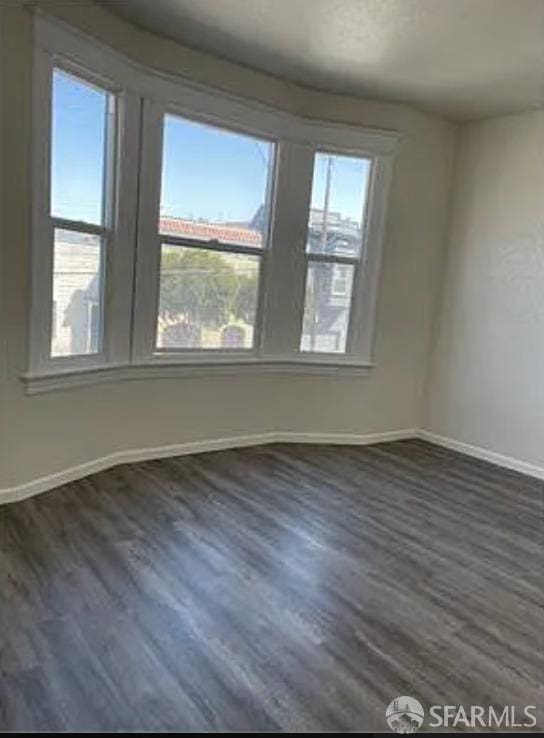 unfurnished room featuring baseboards and dark wood finished floors