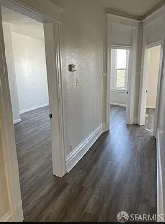 hallway featuring dark wood-type flooring and baseboards