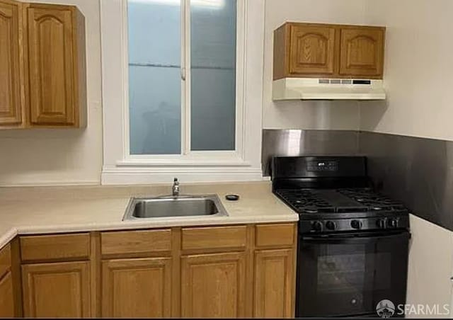 kitchen with black range with gas stovetop, light countertops, under cabinet range hood, and a sink