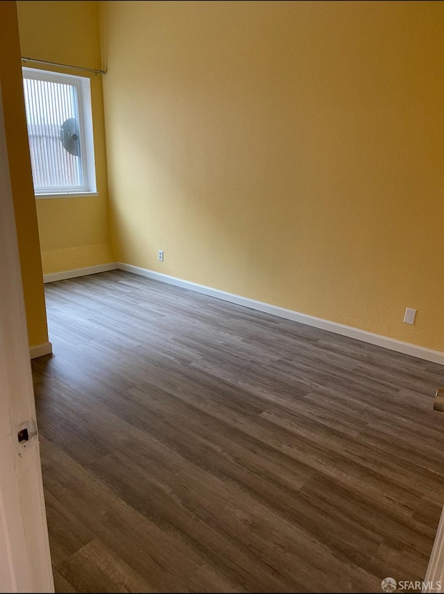 empty room with dark wood-style floors and baseboards