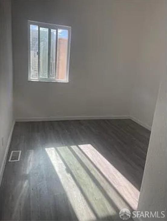 spare room with wood finished floors, baseboards, and visible vents