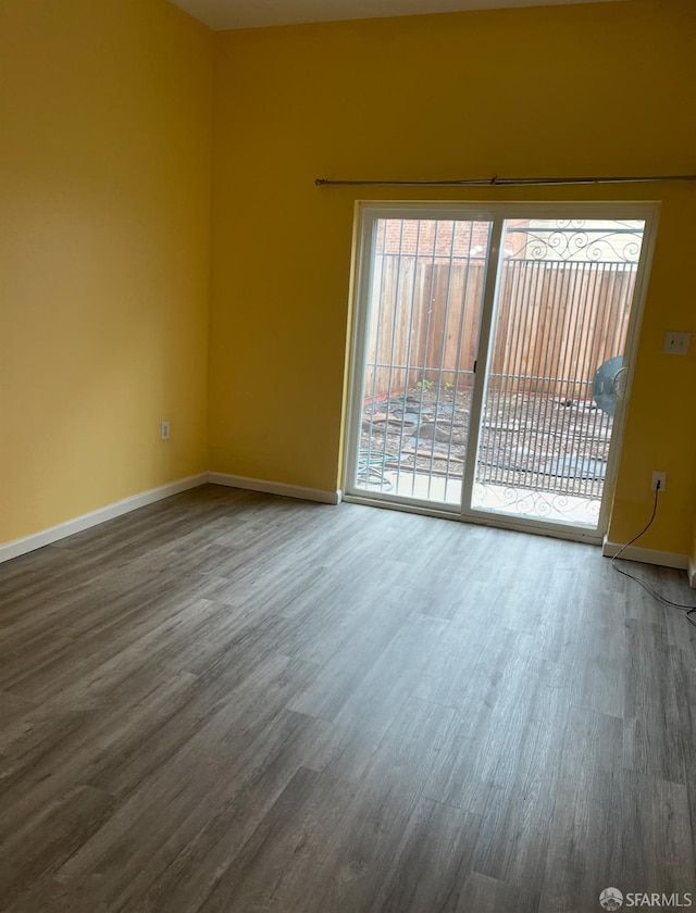 spare room featuring baseboards and wood finished floors