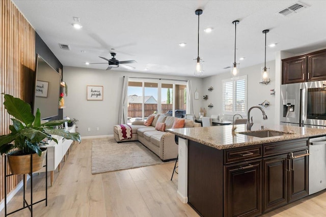 kitchen with a center island with sink, sink, ceiling fan, decorative light fixtures, and stainless steel appliances