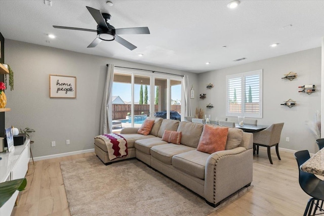 living room featuring a textured ceiling, light hardwood / wood-style flooring, ceiling fan, and a healthy amount of sunlight