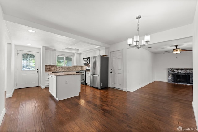 kitchen featuring pendant lighting, white cabinetry, appliances with stainless steel finishes, dark hardwood / wood-style floors, and ceiling fan with notable chandelier