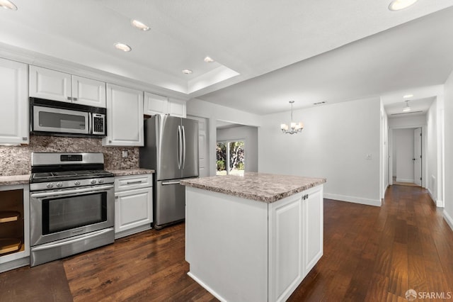 kitchen featuring pendant lighting, stainless steel appliances, white cabinets, and dark wood-type flooring