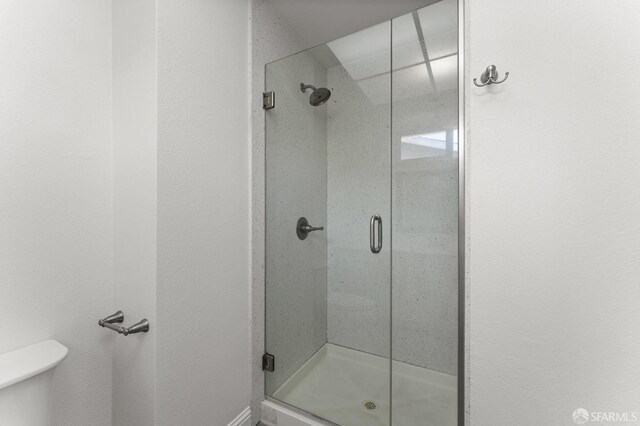 bathroom featuring a shower with shower door and toilet