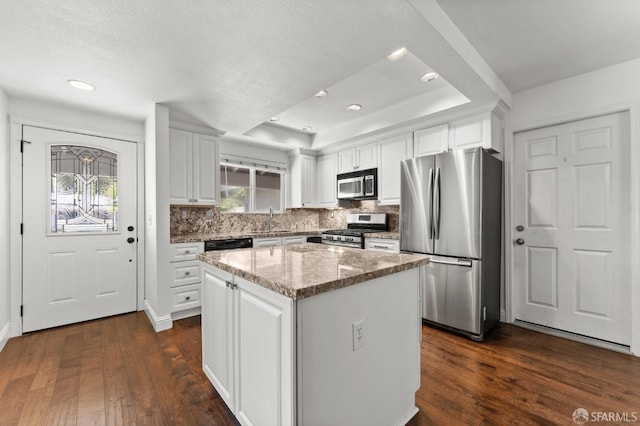 kitchen featuring appliances with stainless steel finishes, a kitchen island, dark wood-type flooring, and white cabinetry