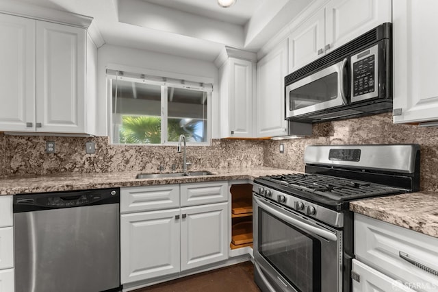 kitchen with sink, tasteful backsplash, white cabinetry, stainless steel appliances, and light stone countertops