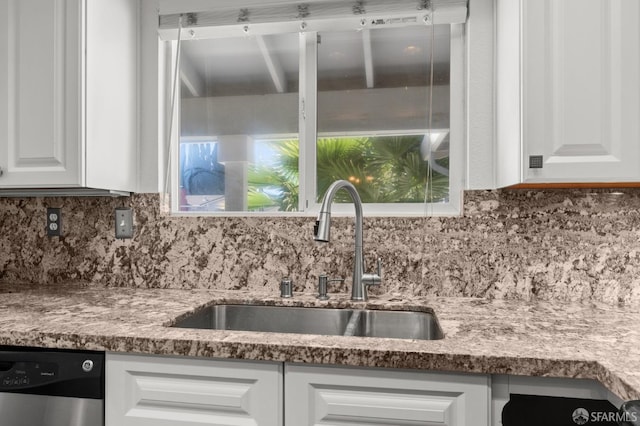 kitchen featuring backsplash, stainless steel dishwasher, sink, and white cabinets