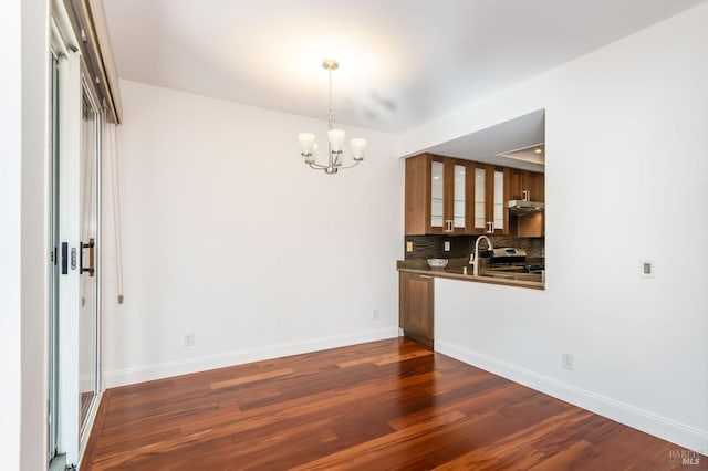 interior space with baseboards, decorative backsplash, brown cabinets, dark wood-type flooring, and stainless steel stove