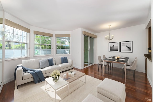 living room featuring baseboards, plenty of natural light, an inviting chandelier, and wood finished floors