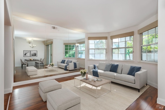 living area with visible vents, a notable chandelier, baseboards, and wood finished floors