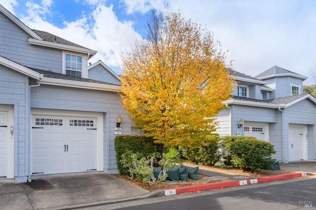 townhome / multi-family property featuring a garage, roof with shingles, and driveway