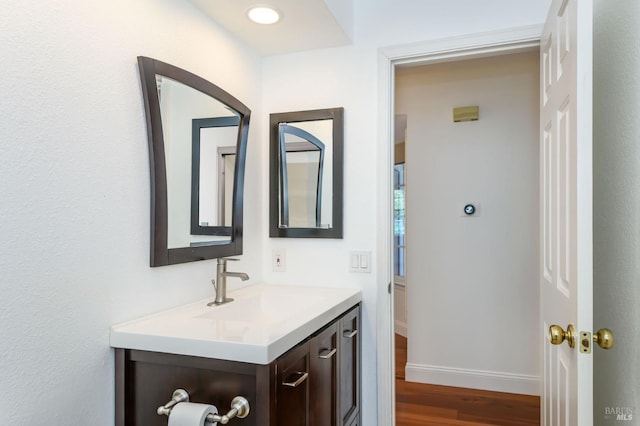 bathroom with baseboards, wood finished floors, and vanity