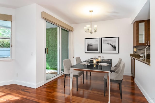 dining space with dark wood finished floors, baseboards, and an inviting chandelier