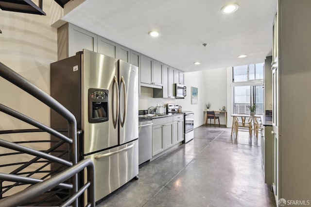 kitchen featuring appliances with stainless steel finishes, a sink, finished concrete flooring, gray cabinets, and recessed lighting