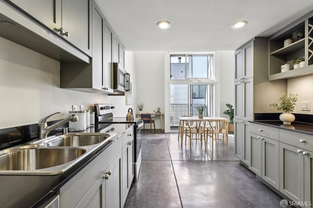 kitchen featuring stainless steel appliances, gray cabinets, dark countertops, and a sink