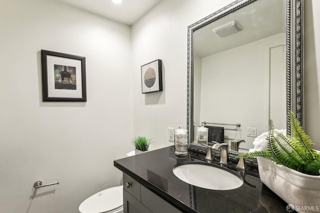half bathroom with vanity, toilet, and visible vents